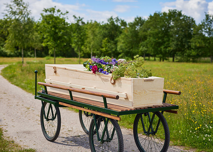 Loopkoets buiten met kist waarop bloemen liggen
