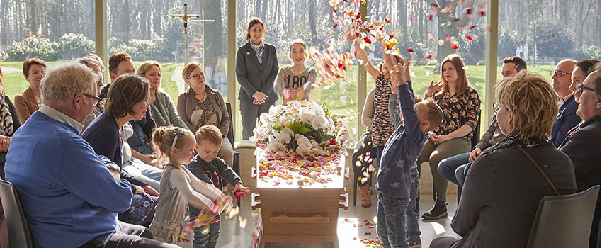 Kinderen strooien bloemblaadjes over de kist tijdens de ceremonie