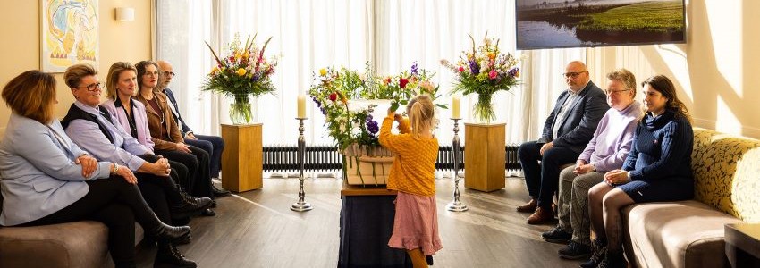 Nabestaanden rondom de kist van hun dierbare bij een ingetogen en eenvoudige uitvaart
