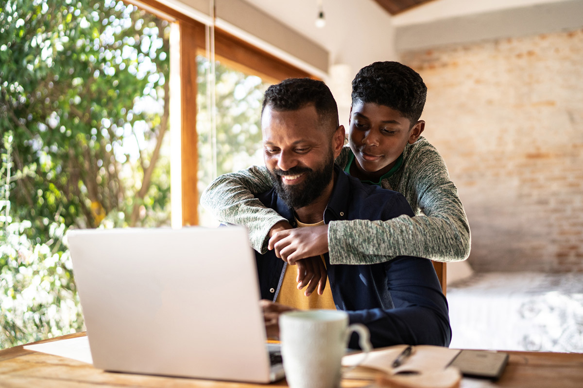 Vader en zoon verdiepen zich op de laptop in een uitvaartverzekering