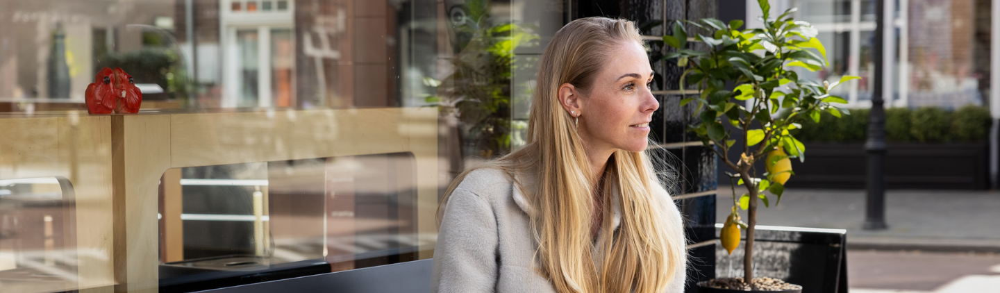 Vrouw zit op bankje en kijkt in de verte